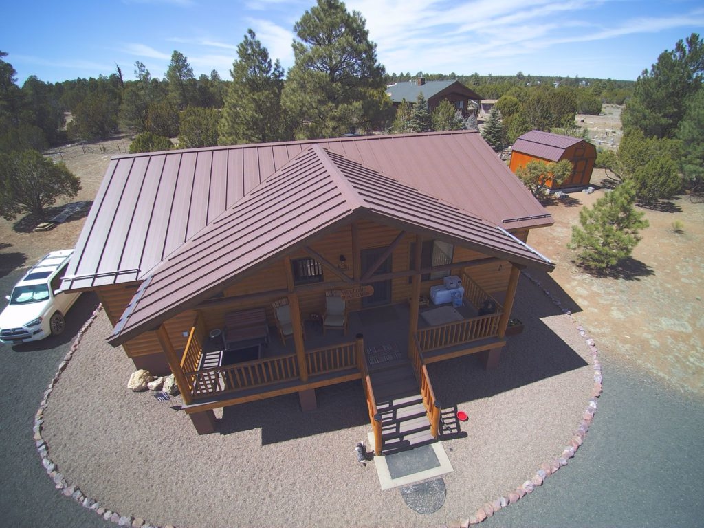 a log cabin with a deep red metal roof.