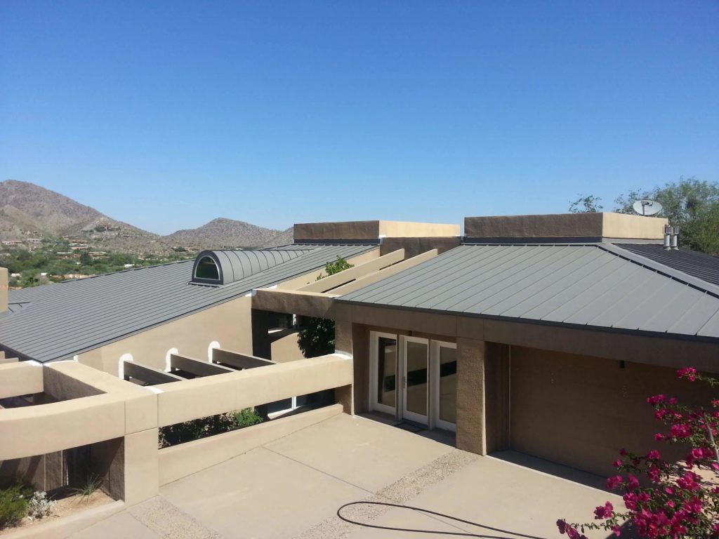 a modern home with a standing seam metal roof with a curved dormer.