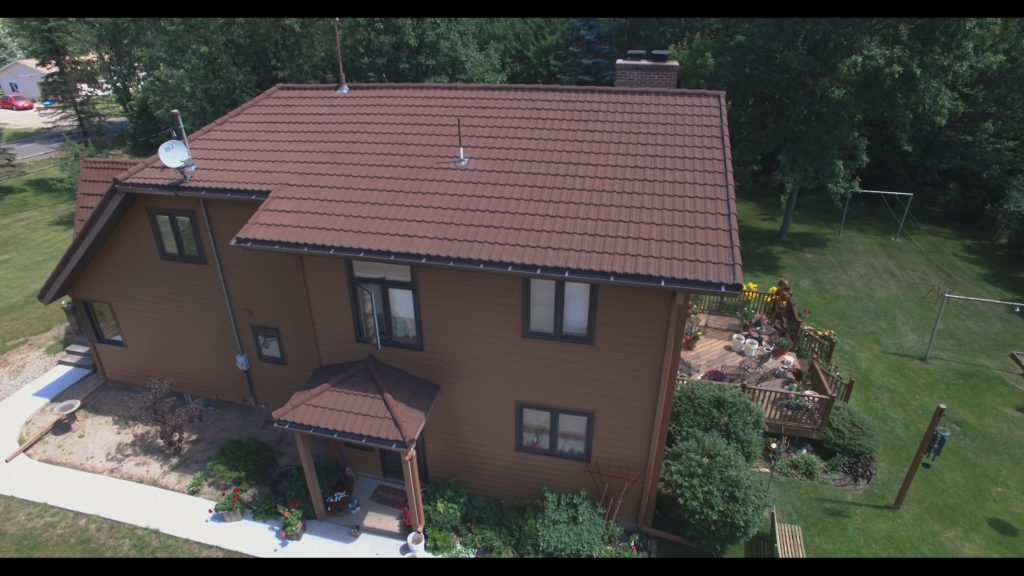 A brown stone coated steel roof that looks like roofing tiles.