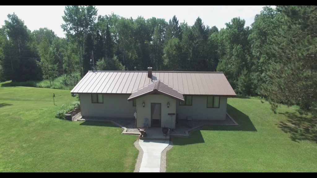 A medium brown standing seam metal roof on a tan house.