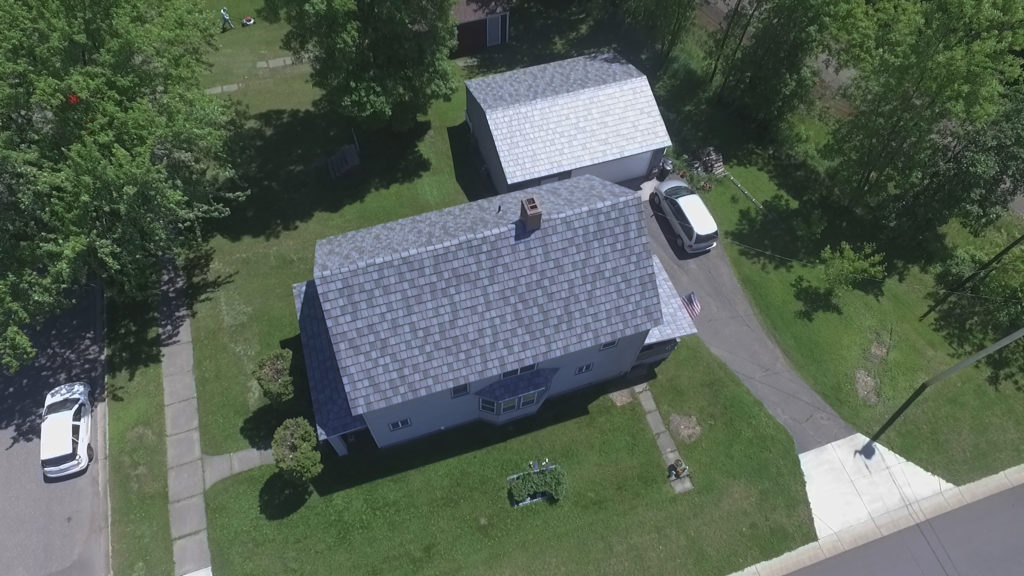 variegated gray metal slate roofs on a home and garage.