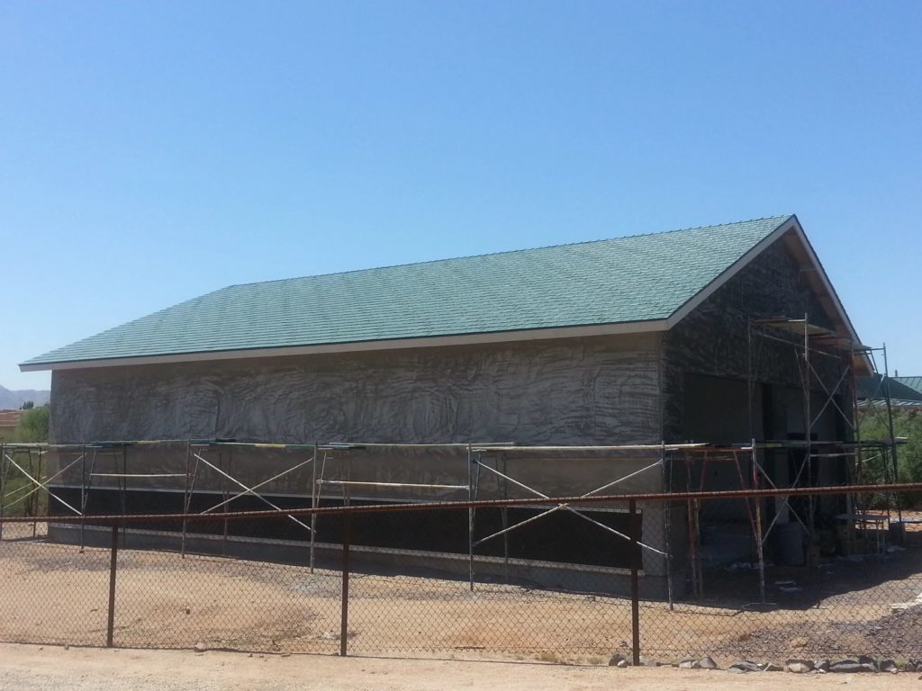 a large garage with a green metal shake roof.