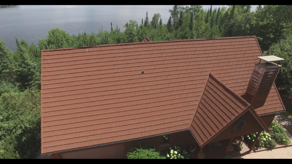 Overhead view of a mountain home surrounded by woods and a lake with a new stone coated steel roof installed by Vertex Metal Roofing