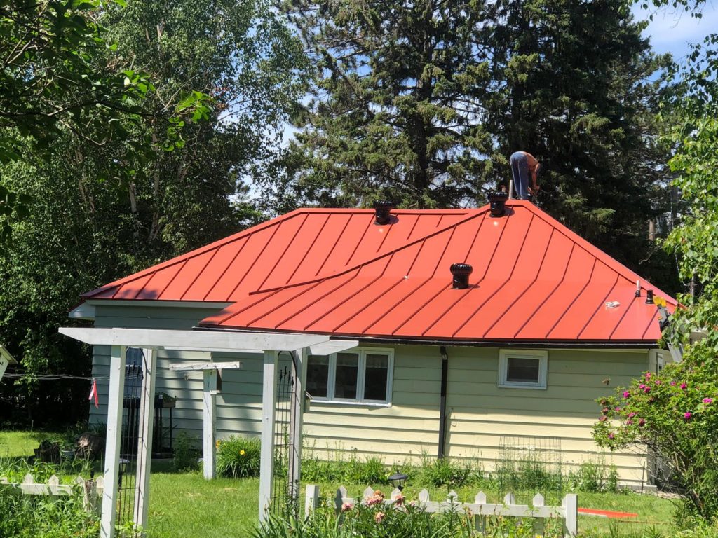 A home with a red standing seam metal roof installed by Vertex Roofing