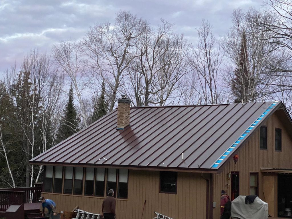 A project with a new brown standing seam metal roof being installed.