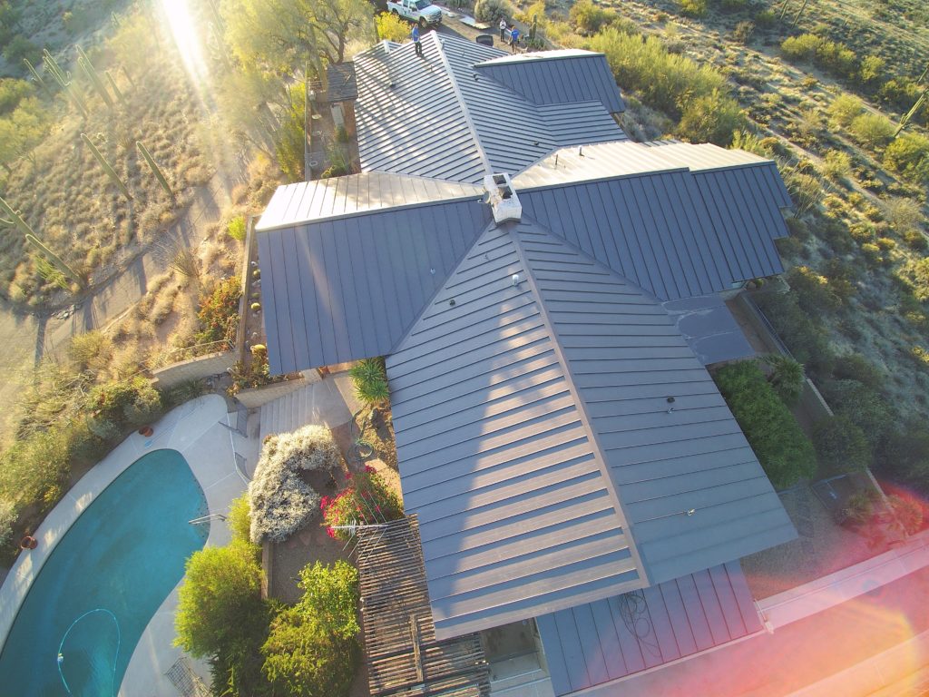 An overhead view of a home with a new standing seam metal roof and a swimming pool in the back yard.