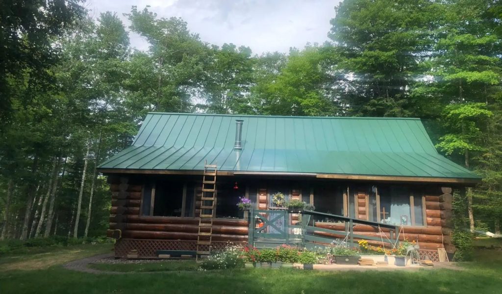 a log cabin with a green standing seam metal roof.